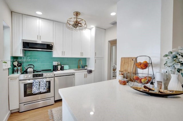 1222 S 14th Ct S, Lake Worth, FL 33460 - kitchen featuring stainless steel appliances, a sink, white cabinets, light countertops, and recessed lighting