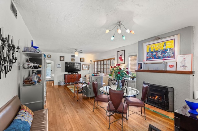 1510 Madrid St, Coral Gables, FL 33134 - dining area with a textured ceiling, hardwood / wood-style floors, a warm lit fireplace, a chandelier, and ceiling fan