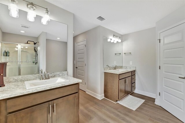 2316 SW Santana Ave, Port St Lucie, FL 34953 - bathroom featuring wood finished floors, a shower stall, two vanities, and baseboards
