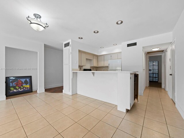 16380 Briar Patch Pl, Miami Lakes, FL 33014 - kitchen with white refrigerator, a peninsula, light tile patterned floors, light countertops, and a kitchen breakfast bar