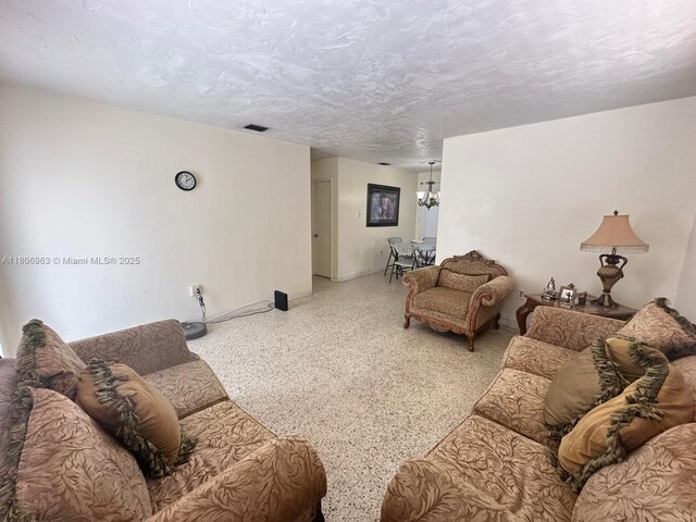 732 Burlington St, Opa-Locka, FL 33054 - living room with speckle patterned floor, a chandelier, and baseboards