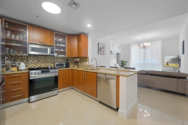 1945 S Ocean Dr Unit 404, Hallandale Beach, FL 33009 - kitchen featuring stainless steel appliances, a sink, a peninsula, decorative backsplash, and brown cabinets