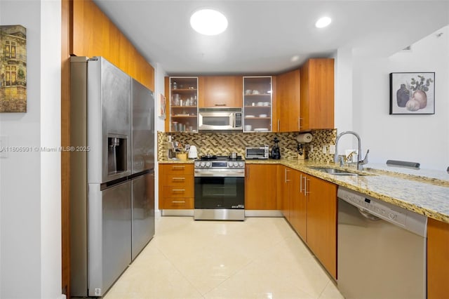1945 S Ocean Dr Unit 404, Hallandale Beach, FL 33009 - kitchen featuring stainless steel appliances, a sink, light stone counters, decorative backsplash, and brown cabinets