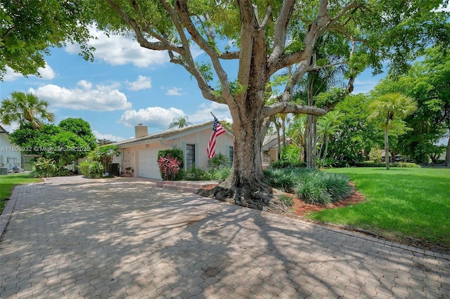 9620 E Calusa Club Dr, Miami, FL 33186 - view of front of home featuring a garage, a front lawn, decorative driveway, a chimney, and cooling unit