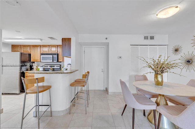 770 Claughton Island Dr Unit 1409, Miami, FL 33131 - kitchen with appliances with stainless steel finishes, a kitchen bar, a peninsula, brown cabinets, and baseboards
