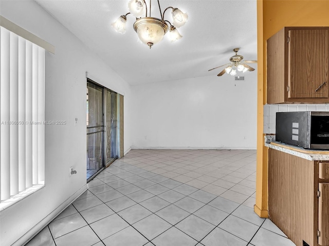 3034 NW 204th Ter, Miami Gardens, FL 33056 - kitchen featuring stainless steel microwave, light countertops, brown cabinets, ceiling fan, and light tile patterned flooring