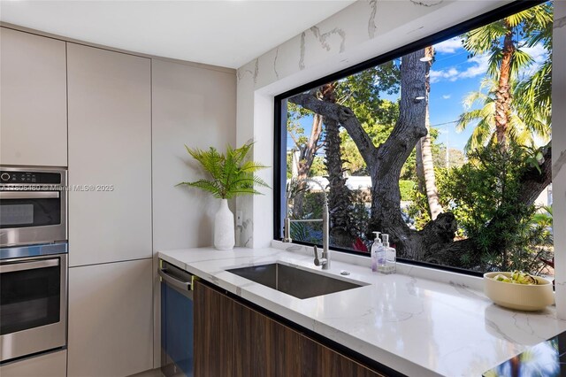 210 NE 107th St, Miami Shores, FL 33161 - kitchen featuring modern cabinets, a sink, light stone counters, and stainless steel appliances