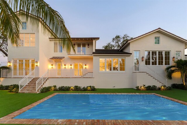 1051 San Pedro Ave, Coral Gables, FL 33156 - rear view of house with stairway, a lawn, french doors, and a covered pool