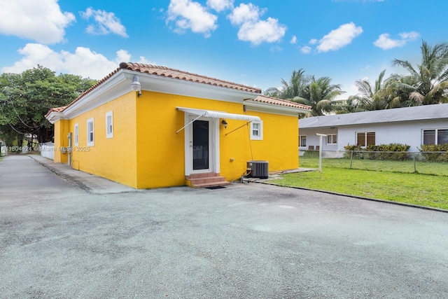 2757 NW 29th St, Miami, FL 33142 - rear view of house with entry steps, a tiled roof, central air condition unit, and stucco siding