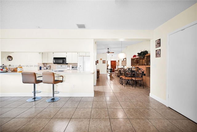 43 NW 109th Ct, Miami, FL 33172 - kitchen featuring white appliances, light tile patterned flooring, a breakfast bar, light countertops, and white cabinets