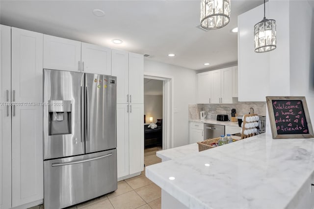 7531 Simms St, Hollywood, FL 33024 - kitchen with appliances with stainless steel finishes, a chandelier, white cabinets, decorative backsplash, and light stone counters