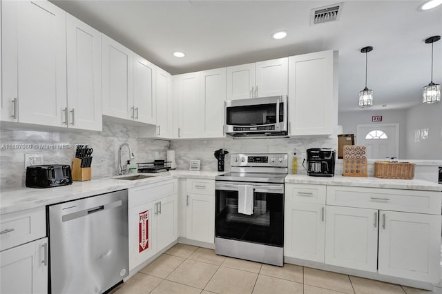 7531 Simms St, Hollywood, FL 33024 - kitchen with stainless steel appliances, a sink, light tile patterned floors, white cabinets, and backsplash