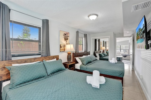 7531 Simms St, Hollywood, FL 33024 - bedroom with multiple windows, a textured ceiling, a closet, light tile patterned floors, and baseboards