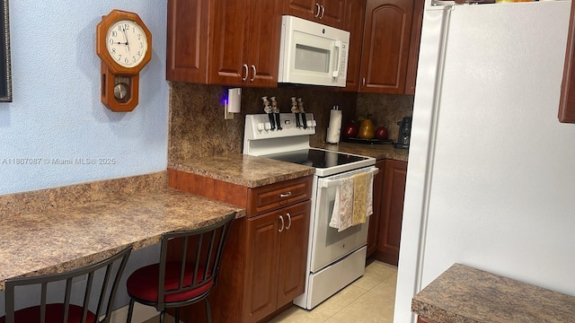 1560 W 46th St Unit 229, Hialeah, FL 33012 - kitchen featuring white appliances, light tile patterned floors, dark countertops, a breakfast bar, and decorative backsplash