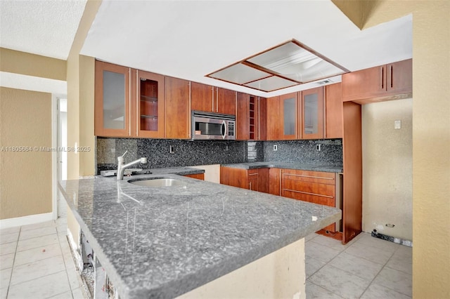 9033 SW 123rd Ct Unit 101, Miami, FL 33186 - kitchen featuring stainless steel microwave, brown cabinetry, a sink, and dark stone counters