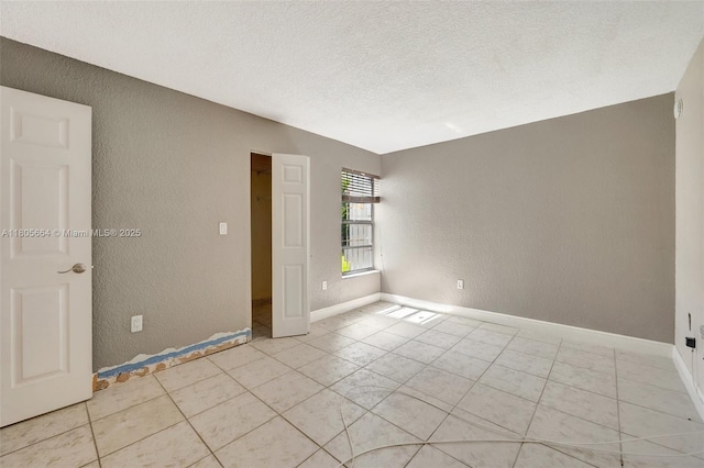 9033 SW 123rd Ct Unit 101, Miami, FL 33186 - empty room featuring a textured wall, light tile patterned floors, a textured ceiling, and baseboards