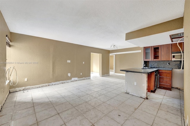 9033 SW 123rd Ct Unit 101, Miami, FL 33186 - kitchen with stainless steel microwave, backsplash, dark countertops, glass insert cabinets, and light tile patterned floors