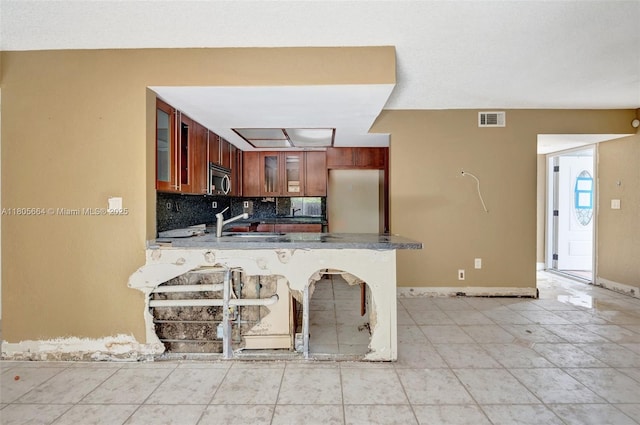 9033 SW 123rd Ct Unit 101, Miami, FL 33186 - kitchen with glass insert cabinets, tasteful backsplash, a peninsula, stainless steel microwave, and baseboards