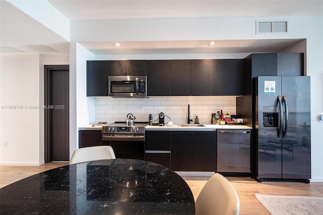 398 NE 5th St Unit 4518, Miami, FL 33132 - kitchen with appliances with stainless steel finishes, a sink, light wood finished floors, tasteful backsplash, and recessed lighting