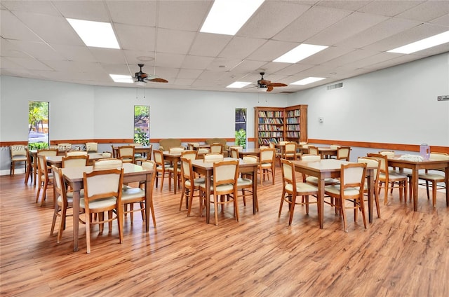 100 Ashbury Rd Unit 103, Hollywood, FL 33024 - dining room with light wood finished floors, ceiling fan, a paneled ceiling, and a wainscoted wall