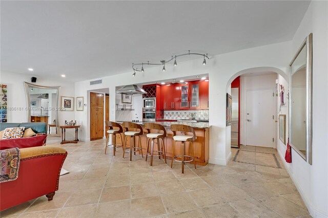 200 Ocean Lane Dr Unit 305, Key Biscayne, FL 33149 - kitchen featuring appliances with stainless steel finishes, decorative backsplash, arched walkways, recessed lighting, and a kitchen breakfast bar