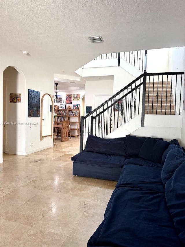 826 E Spinnaker Dr E, Hollywood, FL 33019 - living area featuring stairway, a textured ceiling, arched walkways, and baseboards