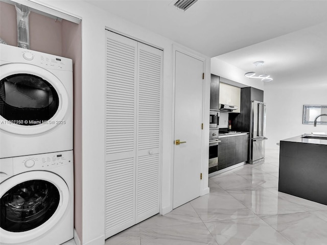 9821 E Bay Harbor Dr Unit 302, Bay Harbor Islands, FL 33154 - laundry room with estacked washer and dryer and light marble finish flooring