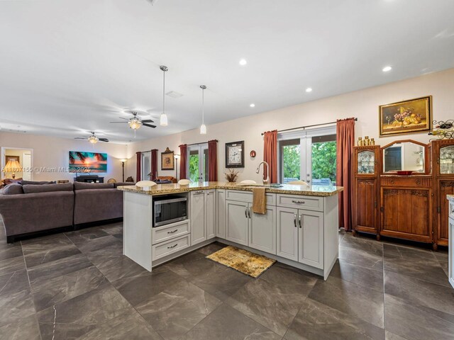15150 SW 240th St, Homestead, FL 33032 - kitchen featuring stainless steel microwave, open floor plan, light stone countertops, recessed lighting, and pendant lighting