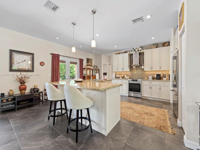 15150 SW 240th St, Homestead, FL 33032 - kitchen featuring appliances with stainless steel finishes, white cabinets, wall chimney range hood, decorative backsplash, and a breakfast bar area