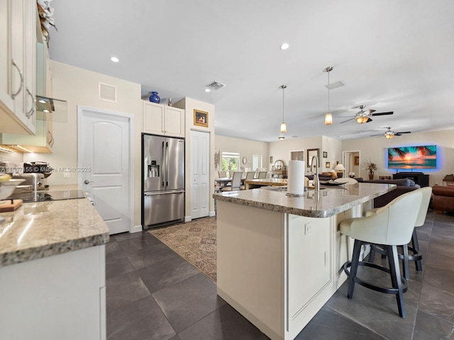 15150 SW 240th St, Homestead, FL 33032 - kitchen featuring high end fridge, a kitchen bar, open floor plan, a ceiling fan, and white cabinets