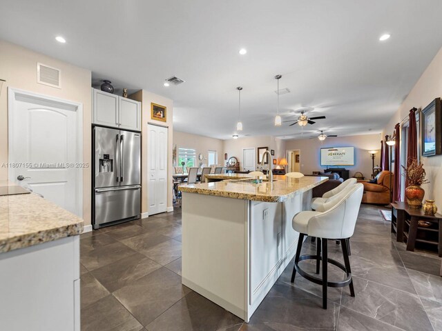 15150 SW 240th St, Homestead, FL 33032 - kitchen featuring stainless steel fridge with ice dispenser, light stone counters, a kitchen breakfast bar, a ceiling fan, and recessed lighting