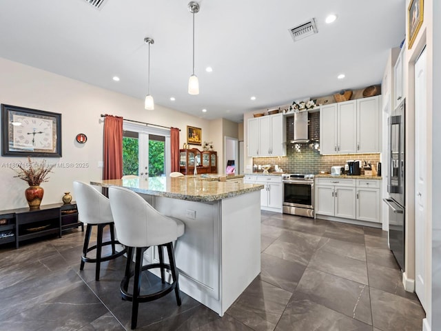 15150 SW 240th St, Homestead, FL 33032 - kitchen with stainless steel appliances, wall chimney exhaust hood, white cabinets, decorative backsplash, and a kitchen island with sink