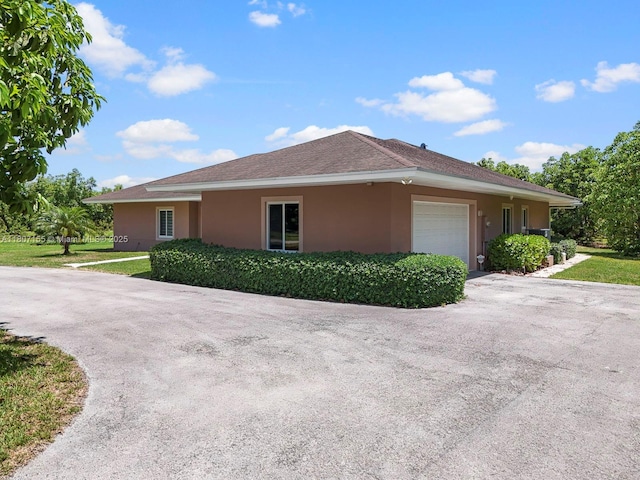 15150 SW 240th St, Homestead, FL 33032 - view of property exterior with stucco siding, a garage, driveway, and a lawn