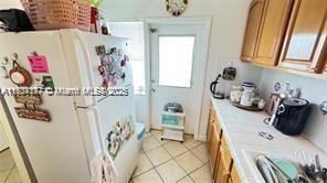 2200 N Park Ln Unit 311, Hollywood, FL 33021 - kitchen featuring freestanding refrigerator, light countertops, brown cabinetry, and light tile patterned floors