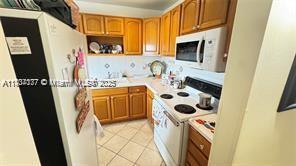 2200 N Park Ln Unit 311, Hollywood, FL 33021 - kitchen featuring white appliances, light tile patterned floors, light countertops, and brown cabinetry