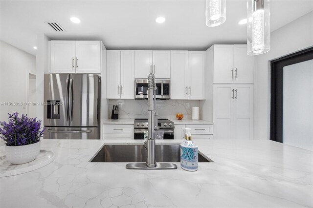 9240 SW 57th Ter, Miami, FL 33173 - kitchen featuring appliances with stainless steel finishes, white cabinetry, light stone countertops, backsplash, and recessed lighting