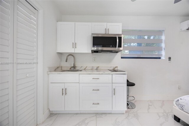 9240 SW 57th Ter, Miami, FL 33173 - kitchen with light marble finish floors, stainless steel microwave, a sink, white cabinetry, and light stone counters