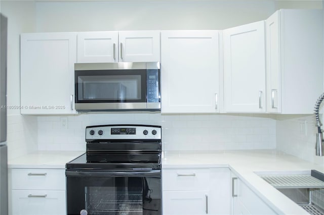 5141 W Oakland Park Blvd Unit 210, Lauderdale Lakes, FL 33313 - kitchen featuring stainless steel microwave, black electric range oven, white cabinetry, decorative backsplash, and light countertops