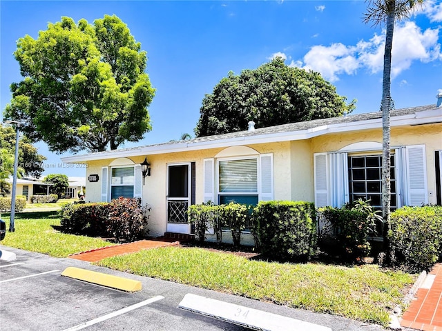 13785 Flora Pl Unit A, Delray Beach, FL 33484 - view of front of home featuring stucco siding, a front lawn, and uncovered parking