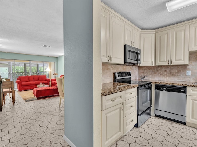 13785 Flora Pl Unit A, Delray Beach, FL 33484 - kitchen with appliances with stainless steel finishes, open floor plan, a textured ceiling, decorative backsplash, and cream cabinetry