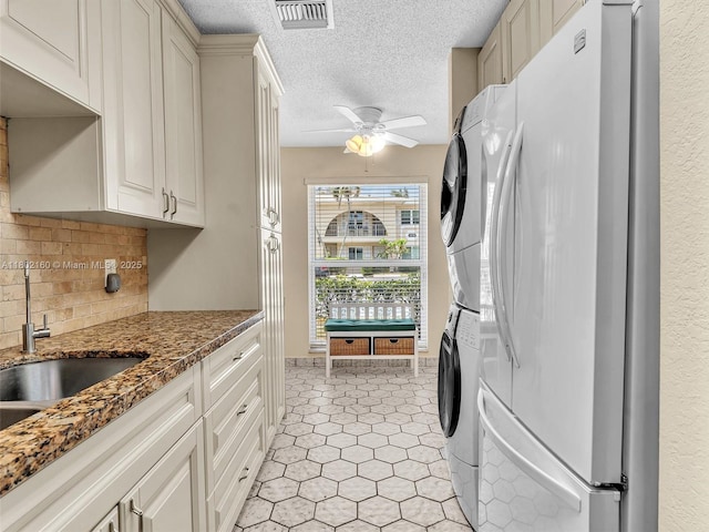 13785 Flora Pl Unit A, Delray Beach, FL 33484 - kitchen with freestanding refrigerator, stacked washer and clothes dryer, ceiling fan, tasteful backsplash, and a textured ceiling