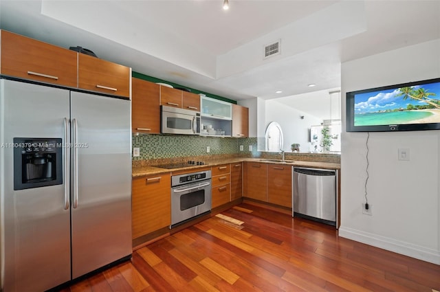 3330 NE 190th St Unit 717, Aventura, FL 33180 - kitchen with appliances with stainless steel finishes, dark wood finished floors, tasteful backsplash, a sink, and brown cabinets