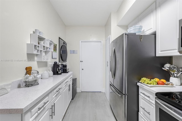 8252 NW 191st Ln Unit 15R, Hialeah, FL 33015 - kitchen with light wood-style flooring, white cabinets, light countertops, stacked washer / drying machine, and stainless steel electric range oven