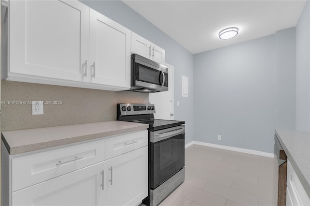 4400 Hillcrest Dr Unit 107A, Hollywood, FL 33021 - kitchen featuring stainless steel appliances, white cabinetry, light stone counters, baseboards, and light tile patterned flooring