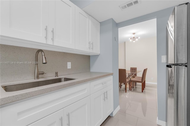 4400 Hillcrest Dr Unit 107A, Hollywood, FL 33021 - kitchen featuring freestanding refrigerator, a sink, baseboards, light tile patterned floors, and white cabinetry