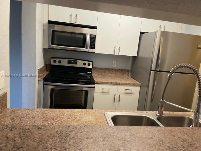 927 Riverside Dr Unit 326, Coral Springs, FL 33071 - kitchen featuring stainless steel appliances, light countertops, white cabinets, and a sink