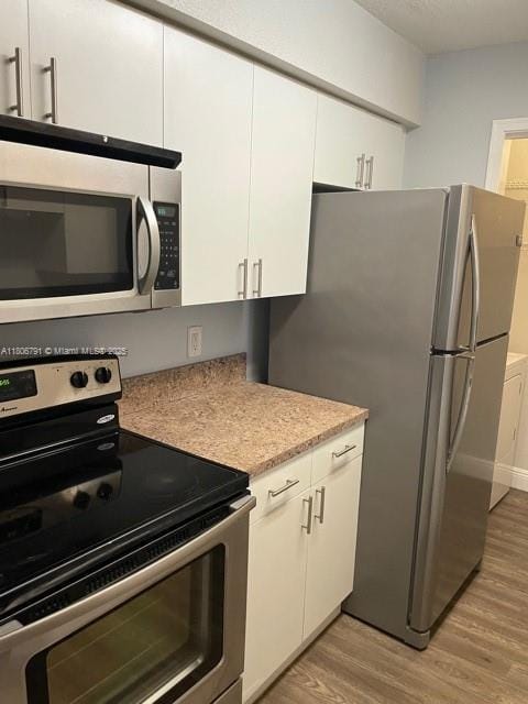 927 Riverside Dr Unit 326, Coral Springs, FL 33071 - kitchen with stainless steel appliances, light wood-style flooring, white cabinets, and light countertops