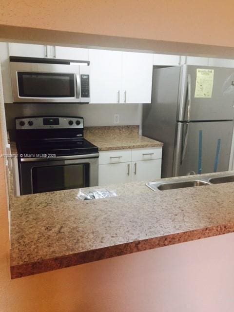 927 Riverside Dr Unit 326, Coral Springs, FL 33071 - kitchen with stainless steel appliances, white cabinets, a sink, and light stone counters