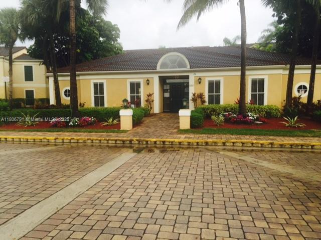927 Riverside Dr Unit 326, Coral Springs, FL 33071 - view of front facade with stucco siding, a tile roof, and uncovered parking