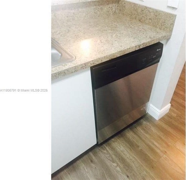 927 Riverside Dr Unit 326, Coral Springs, FL 33071 - kitchen view of stainless steel dishwasher, light wood-style floors, light countertops, a sink, and baseboards